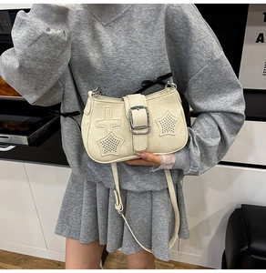 Detail of beige shoulder bag with silver metal studs and large buckle closure