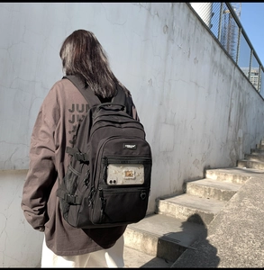 Détail du sac à dos noir en toile avec poches en filet et boucles de réglage latérales