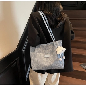 Close-up of floral tote bag with woven rope handles and a plush cloud charm detail