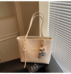 Close-up of cream lychee texture tote bag featuring a cute teddy bear charm