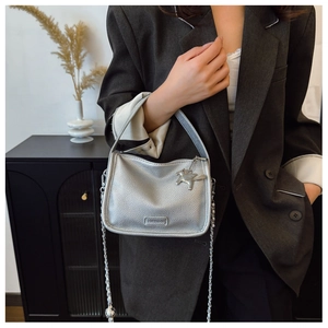 Detail of silver textured mini bag with metallic horse charm and silver chain strap