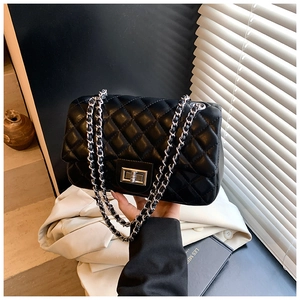 Detail view of black quilted leather crossbody bag with silver twist lock and chain strap