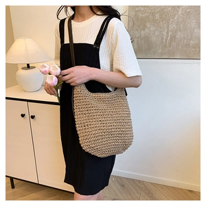 Détail de la texture du sac seau en paille et bandoulière en cuir sur un modèle