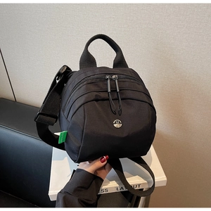 Close-up of black waterproof nylon bag with multi-pocket zippers and metal M logo