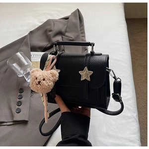 Détail du sac à main noir grainé avec boucles en étoile et pendentif ours en peluche