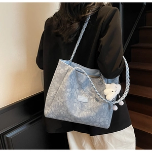 Detail of light blue floral tote bag with braided strap and cloud charm on model