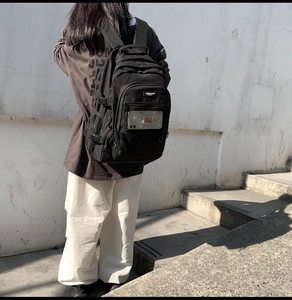 Détail d'un grand sac à dos en nylon noir avec plusieurs poches zippées fonctionnelles