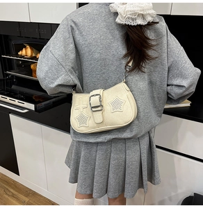 Detailed close-up of cream PU leather bag with silver star rivets and buckle strap