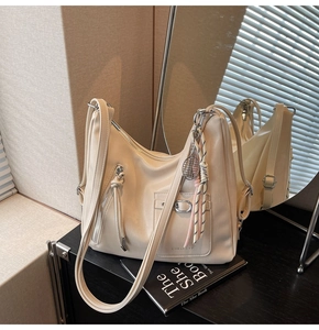 Detailed macro view of cream hobo bag with tennis racket charm and silver metal zippers