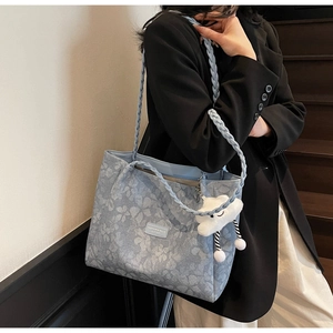 Close-up of light blue floral jacquard tote bag with woven handles and cloud charm