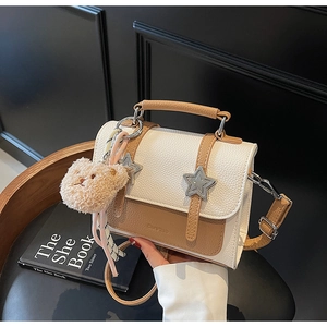 Détail du sac bandoulière bicolore avec texture grainée et accents d'étoiles