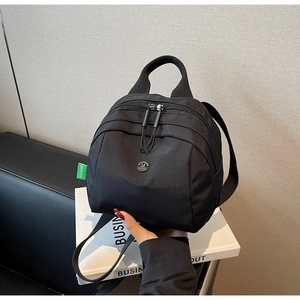 Close-up of black nylon mini shell bag with metal logo and durable zipper detail
