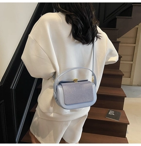 Detail of lavender patchwork crossbody bag with golden round twist lock on a model