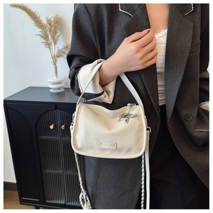 Detail of cream textured leather crossbody bag with silver horse charm and chain strap
