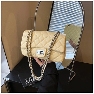 Close-up of beige quilted crossbody bag with silver chain strap and metal turn-lock