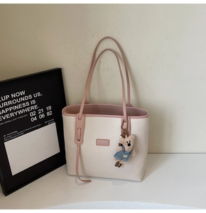 Detail of lychee textured tote bag with pink straps and a cute bear charm accessory