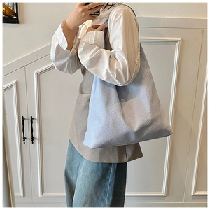 Detail of light blue leather tote bag with lychee texture shown on a model