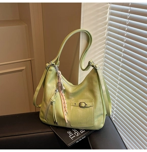 Detail of light green tote bag with matte leather texture and woven cord pendant