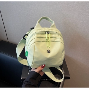 Macro shot of light green waterproof nylon bag with metal logo and wide textile strap