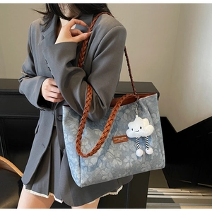 Detail of blue floral tote bag featuring woven leather handles and white cloud charm