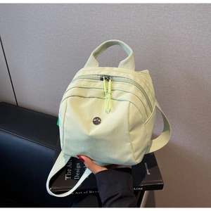 Detailed view of light green nylon mini backpack with top handle and metal logo