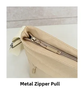 Dettaglio macro della borsa a secchiello in nylon beige con cerniera metallica lucida