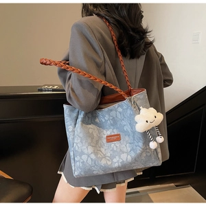 Blue denim tote bag with white floral print, woven straps, and a cute cloud charm