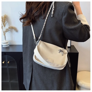 Detail of cream leather crossbody bag with silver horse charm and chain strap