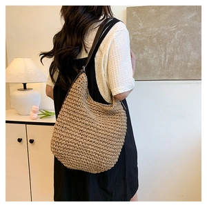 Détail du sac seau en paille tressée montrant la texture naturelle et la bandoulière