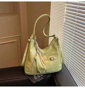 Detail of lime green hobo tote bag featuring decorative tassels and smooth PU leather texture