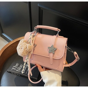 Vue détaillée du sac à main en cuir rose avec boucle étoile argentée et pendentif ours