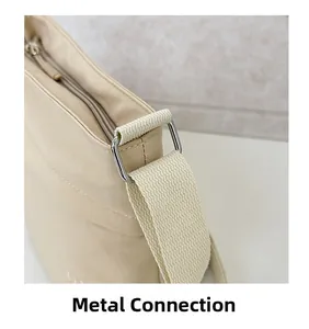 Dettaglio della fibbia in metallo argento e della tracolla in nylon beige della borsa