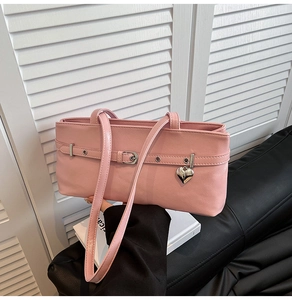 Detail of pink faux leather bag featuring lychee texture and silver heart charm
