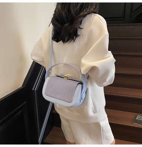 Detail of color-block pillow bag featuring blue leather, purple fabric, and gold clasp