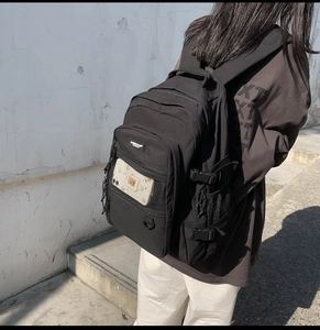 Détail d'un sac à dos noir grande capacité avec boucle latérale et poche filet frontale