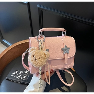 Détail du sac à main rose en cuir grainé avec boucle étoile et breloque ours