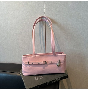 Detailed view of pink leather underarm bag featuring a silver heart charm and metal eyelets