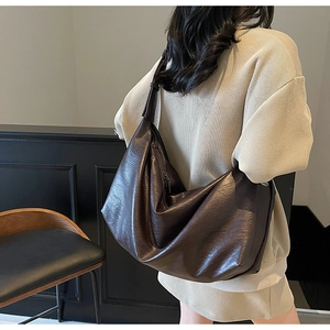 Detail of a dark brown vintage oil wax leather shoulder bag on a female model