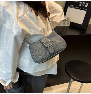 Detail of grey denim shoulder bag with silver star studs and metallic buckle closure