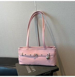 Detail of pink baguette bag with adjustable leather strap and a heart metal pendant