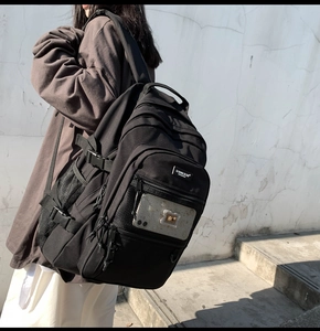 Détail d'un sac à dos noir avec poche en filet et boucle latérale porté par un mannequin