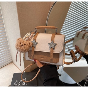 Détail du sac à bandoulière contrasté crème et kaki avec boucles étoiles et ours