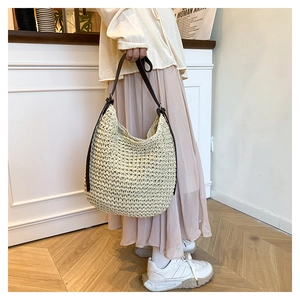 Détail de la texture en paille tressée et bandoulière en cuir marron d'un sac beige