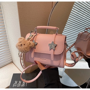 Détail du sac à main en cuir rose avec étoiles argentées et breloque ours peluche