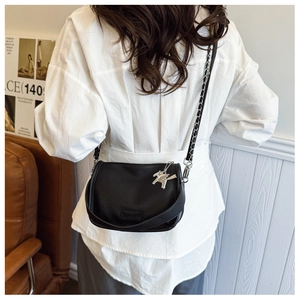 Detailed back view of a black lychee leather crossbody bag with silver horse charm and chain