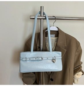Detail of light blue patent leather bag with silver heart charm on a metal hanger