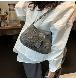 Detail of dark gray crossbody bag with star and cross patches and metal rivet studs