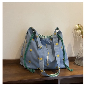 Detail view of floral embroidery on light blue canvas tote bag with drawstring closure