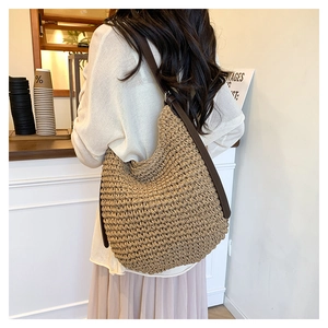 Détail du sac seau en paille tissée main avec bandoulière en cuir marron pour l'été