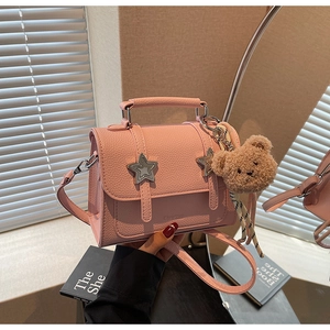 Détail du sac à main rose en cuir grainé avec boucles étoiles et pendentif ours